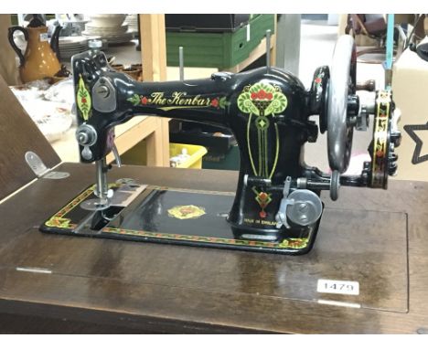 A Vintage manual wind British made sewing machine nicely decorated of Art Nouveau design in a foldaway oak cabinet table.