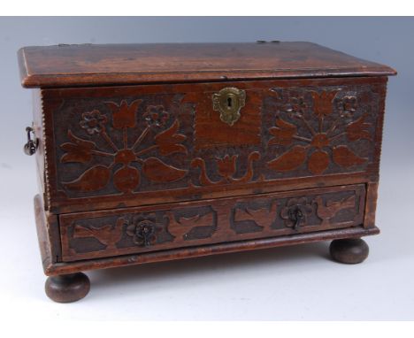 An antique oak Bible box, the hinged cover on steel loop hinges over a blind chip carved front with later cut-in base drawer,