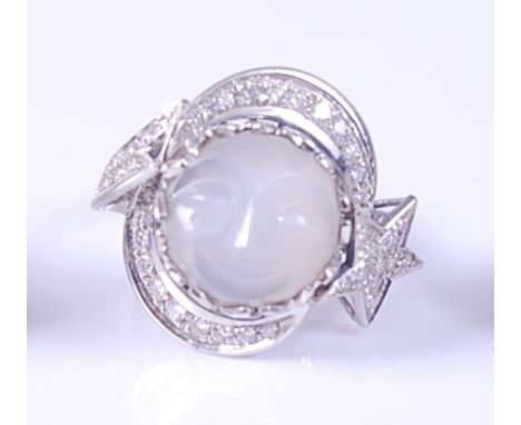 A white metal carved 'man in the moon' moonstone and diamond ring, the centre round moonstone cabochon within a double cresce