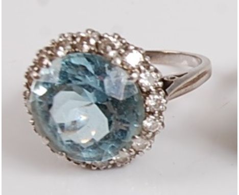 A white metal, aquamarine and diamond circular cluster ring, the centre round faceted aquamarine measuring approx 12.2 x 12.1