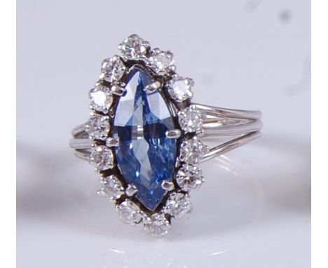 A white metal, sapphire and diamond marquise shaped cluster ring, featuring a centre marquise cut sapphire within a border of