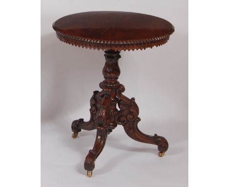 A 19th century Burmese rosewood topped circular fixed pedestal tripod table, with chip carved and fluted edge, over acanthus 