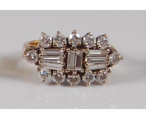 An Art Deco style 18ct gold diamond ring, arranged as eight centre baguettes within a surround of twelve claw set round brill