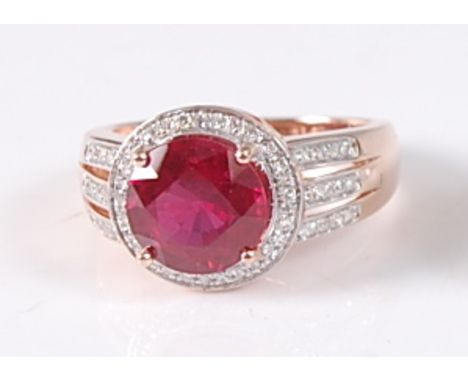 A rose gold, ruby and diamond circular cluster ring, featuring a centre round faceted ruby within a border of 29 single cut d