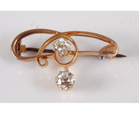 An Art Nouveau yellow metal diamond set bar brooch, featuring two old mine cut diamonds claw set within an open scrollwork su