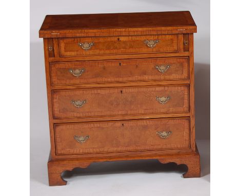 An early Georgian style figured walnut, oak crossbanded and further inlaid bachelors chest, the fold-over top supported by pu