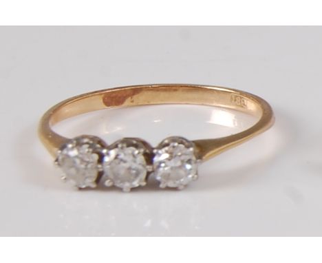 A yellow and white metal diamond trilogy ring, featuring three graduated round brilliant cut diamonds in claw settings, diamo