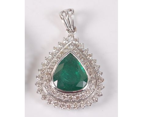 A white metal, emerald and diamond pear shaped cluster pendant, featuring a centre pear cut emerald within two borders of 24 