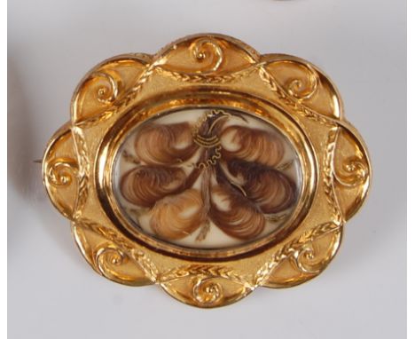 A Victorian yellow metal mourning brooch, centre set with locks of hair under crystal cover within scrolling oval surround, h