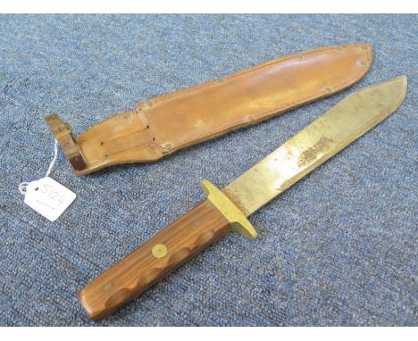 Knife: A large Bowie Knife of 20th century construction. Unmarked blade 11". Plain wood grips secured by a brass rivet. Brass