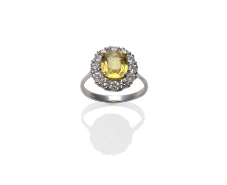 An 18 Carat White Gold Yellow Sapphire and Diamond Cluster Ring, the oval mixed cut sapphire within a border of round brillia