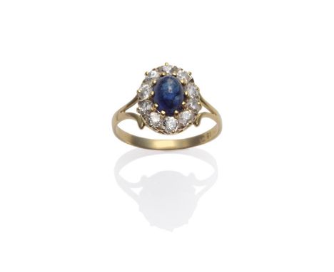 A Sapphire and Diamond Cluster Ring, the oval cabochon sapphire within a border of old cut diamonds in yellow claw settings, 