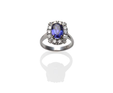 An 18 Carat White Gold Tanzanite and Diamond Cluster Ring, the oval cut tanzanite within a border of round brilliant cut diam