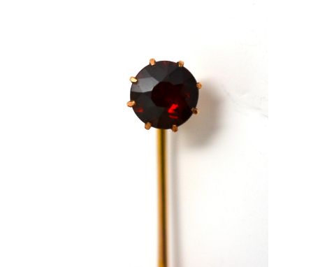 A Stick Pin, in a Wartski case, a round cut garnet in a yellow claw setting, on a pin with mid-way twist This is in good cond