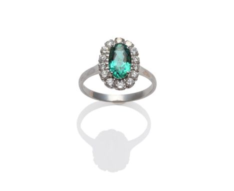 An 18 Carat White Gold Emerald and Diamond Ring, the oval mixed cut emerald within a border of round brilliant cut diamonds, 