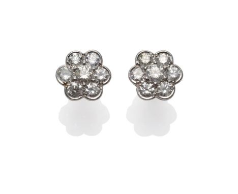 A Pair of Diamond Cluster Earrings, each set with seven round brilliant cut diamonds in a white claw and rubbed over setting,