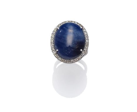 An 18 Carat White Gold Sapphire and Diamond Cluster Ring, the large cabochon sapphire within a border of round brilliant cut 