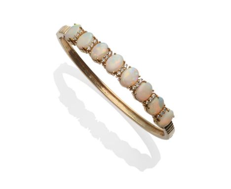 A 14 Carat Gold Opal and Diamond Bangle, eight oval opals spaced by trios of round brilliant cut diamonds in yellow claw sett