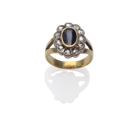 A Synthetic Sapphire and Diamond Cluster Ring, the oval mixed cut sapphire in a yellow rubbed over setting, within a border o