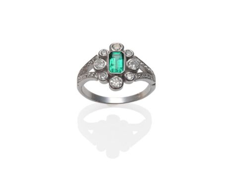 An Emerald and Diamond Cluster Ring, the emerald-cut emerald in a spaced border of old cut diamonds, in white rubbed over set