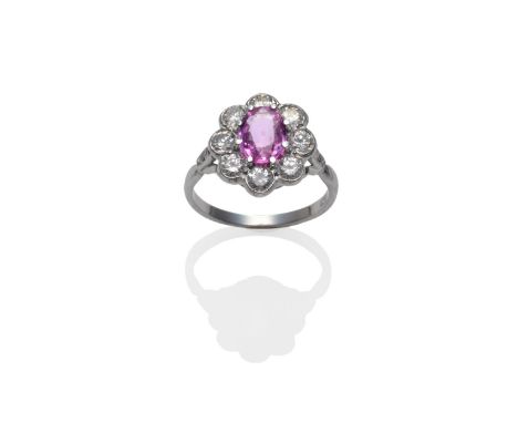 A Pink Sapphire and Diamond Cluster Ring, the oval mixed cut pink sapphire within a border of round brilliant cut diamonds in