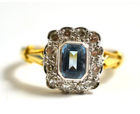 An 18 Carat Gold Aquamarine and Diamond Cluster Ring, the emerald-cut aquamarine within a border of eight-cut diamonds, in wh