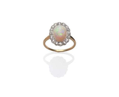 An Opal and Diamond Cluster Ring, an oval cabochon opal within a border of old cut diamonds, in white millegrain settings, on