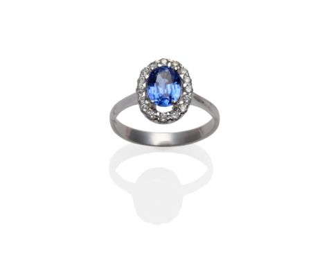 An 18 Carat White Gold Sapphire and Diamond Cluster Ring, the oval mixed cut sapphire within a border of round brilliant cut 