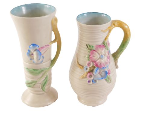 Two Clarice Cliff vases, each on a cream ground decorated with pink and blue flowers, 21cm and 20cm high. (2) 