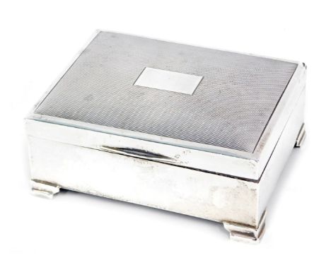 A George VI silver cigarette box, with engine engraved decoration, and a square vacant cartouche, on stepped foot, with a woo