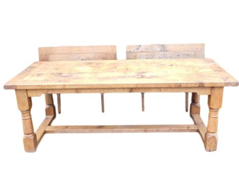 A light oak extending refectory table, with a plank top, shaped apron, on turned supports with flat H stretcher, two leaf ext