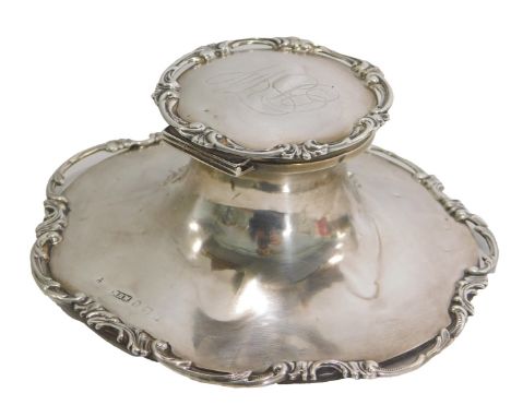 A George V silver inkwell, with c-scroll rococo border to top and base rim, bearing the initials BW, on a weighted base with 