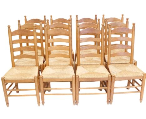 A set of twelve oak ladder back dining chairs, each with a rush seat, on turned legs with stretchers. 