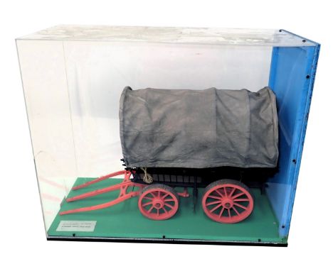 A scale model of an 18thC American stage wagon, polychrome decorated with canvas cover, in glazed Perspex case, 64cm wide. 