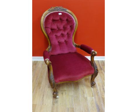 A Victorian walnut open arm chair with button back and padded scrollwork arms, above padded seat raised on moulded feet and c