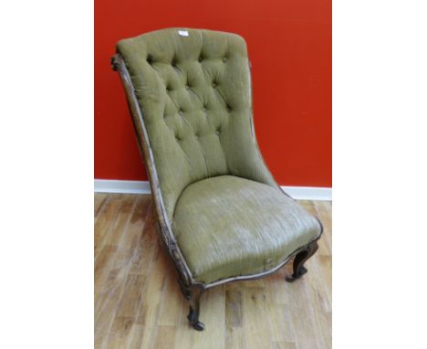 A Victorian mahogany framed button back chair upholstered in green fabric and raised on moulded feet with ceramic castors
