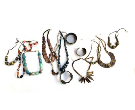 A quantity of bead necklaces, a wooden painted tahon bangle, a heavy cast metal archaistic style bangle set with green hard s