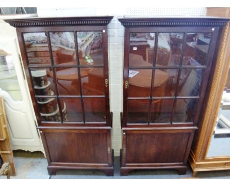 A pair of adapted 18th century mahogany bookcase cupboards, each with dental cornice over single astragal glazed door, on bra