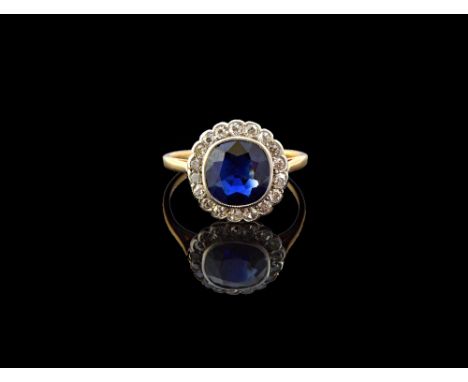 A gold, sapphire and diamond set cluster ring, mounted with the cushion shaped sapphire at the centre, within a surround of s