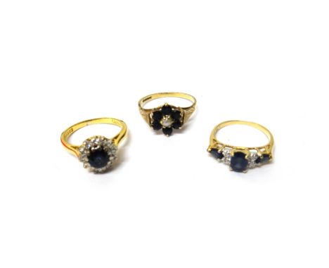 An 18ct gold, sapphire and diamond set cluster ring, claw set with the circular cut sapphire at the centre, in a surround of 