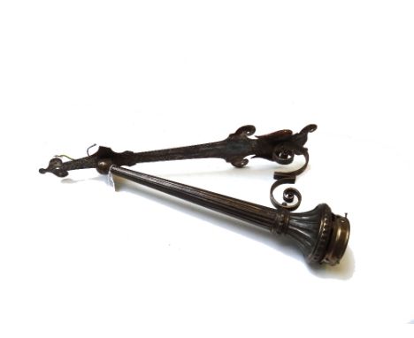 A wrought iron wall light, 20th century, with frosted glass flambe shade over a fluted torch shaft, on a shaped backplate, 69