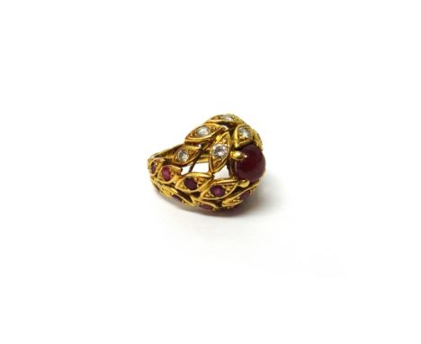 An 18ct gold, ruby and diamond set ring, in a bombe and pierced foliate design, mounted with a circular cabochon ruby at the 