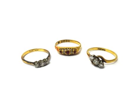 A gold and platinum, diamond set three stone ring, claw set with a row of circular cut diamonds in a crossover design, a gold