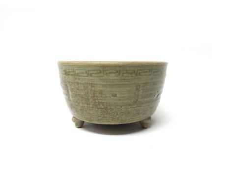 A Chinese celadon glazed censer, Qing Dynasty, of cylindrical form, raised on three scroll supports, moulded on the exterior 