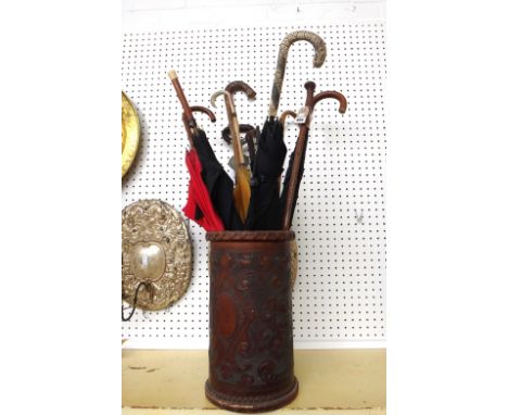 A Victorian embossed leather stick stand and eleven umbrellas and walking sticks, including an umbrella with a gold ferrule, 