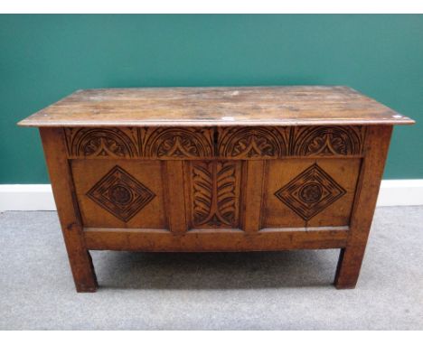 A 17th century oak coffer, with plank top over carved triple panel front, on stile feet, 112cm wide.