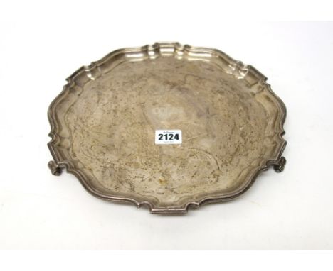 A silver salver, of shaped circular form, with a Chippendale style rim, raised on three scrolling feet, in the 18th century t