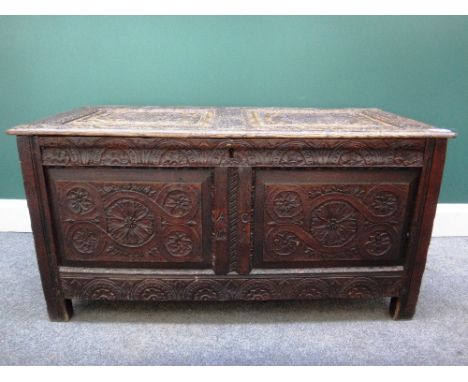 A 17th century oak coffer with a carved double panel lid and front on stile feet, 110cm wide 