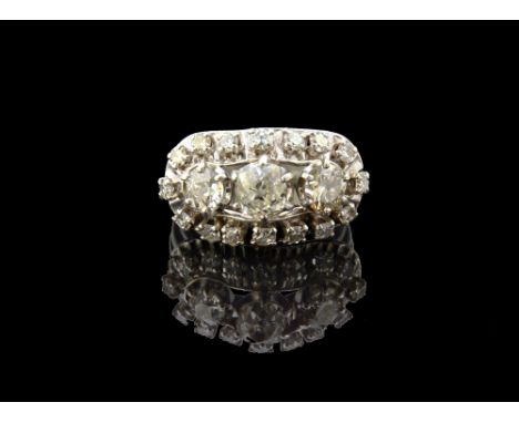 A diamond set ring, claw set with a row of the three principal cushion shaped diamonds at the centre, within an oval openwork