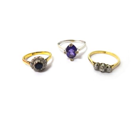 A gold, sapphire and diamond set cluster ring, detailed 18 C, a gold and diamond set three stone ring, claw set with a row of